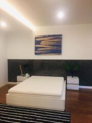 Modern bedroom with wooden flooring and abstract wall art