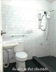 Clean white tiled bathroom with sink, toilet, and shower