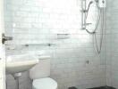 Clean white tiled bathroom with sink, toilet, and shower