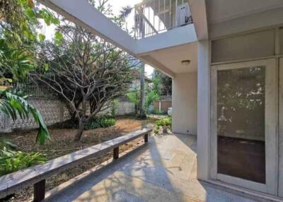 Photo of a backyard with a patio area, trees, and surrounding greenery.