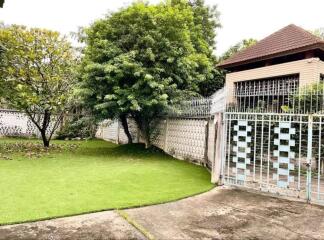 Gated front yard with green lawn and trees