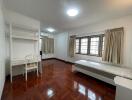 Spacious bedroom with wooden parquet flooring, single bed, desk, chair, and large windows with curtains.