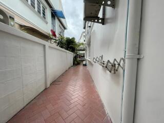 Narrow outdoor walkway with tiled floor and white walls