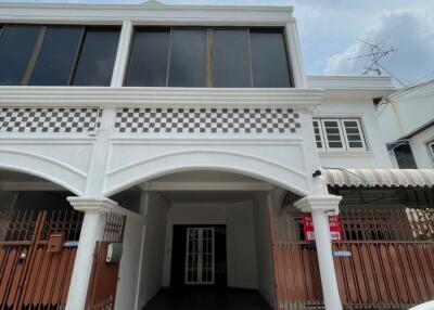 Facade of a two-story white building with tiled patterns and gated entrance