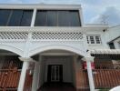 Facade of a two-story white building with tiled patterns and gated entrance