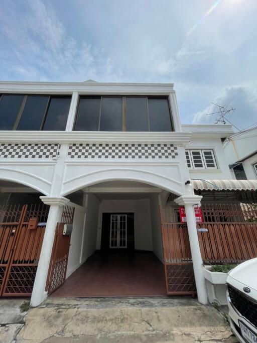 Facade of a two-story white building with tiled patterns and gated entrance