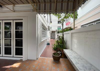 Covered outdoor corridor with potted plants and seating