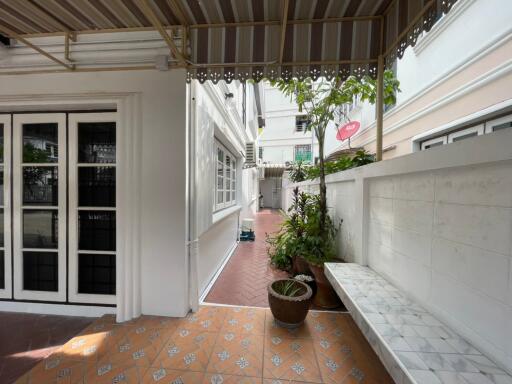 Covered outdoor corridor with potted plants and seating