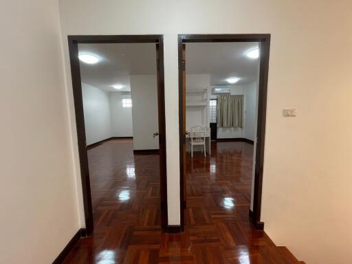 A view of a living space with two doorways leading to separate rooms, featuring wooden floors and white walls.