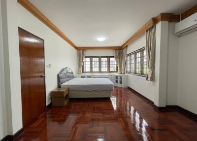 Spacious bedroom with wooden flooring and large windows