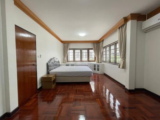 Spacious bedroom with wooden flooring and large windows