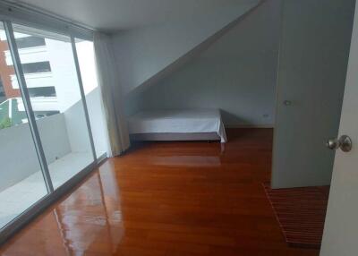 Spacious bedroom with wooden flooring and natural light