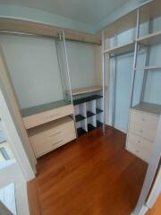 Spacious walk-in closet with wooden flooring and built-in storage units