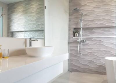 Modern bathroom with a vessel sink, glass shower, and wave-patterned wall tiles