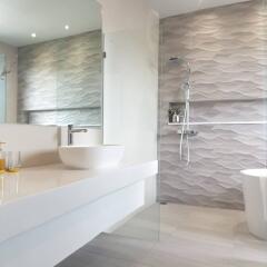 Modern bathroom with a vessel sink, glass shower, and wave-patterned wall tiles