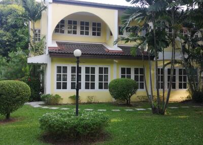 Exterior view of a yellow two-story house with windows and landscaping