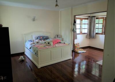 Spacious bedroom with wooden flooring and large windows