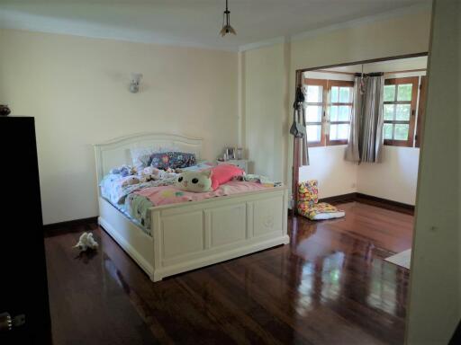 Spacious bedroom with wooden flooring and large windows