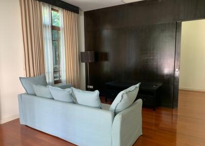 Living room with a light blue sofa, wooden floors, and a large window