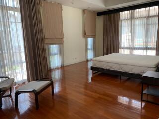 Spacious bedroom with large windows, wooden flooring, and modern furniture.