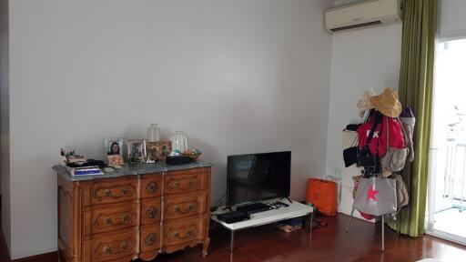 Living room with a wooden dresser, television, and balcony