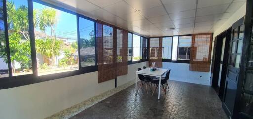 Sunlit enclosed patio with dining table and chairs