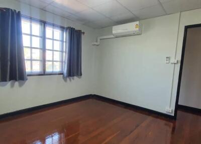 Bedroom with wooden floor, window, and air conditioning