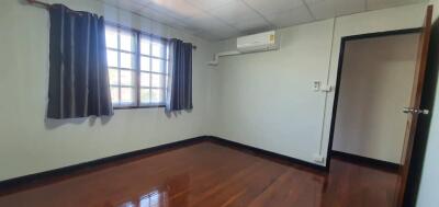 Bedroom with wooden floor, window, and air conditioning