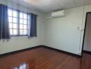 Bedroom with wooden floor, window, and air conditioning