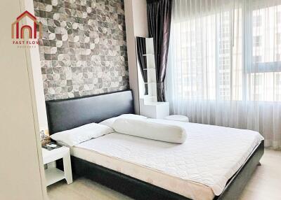 Modern bedroom with patterned accent wall and large windows