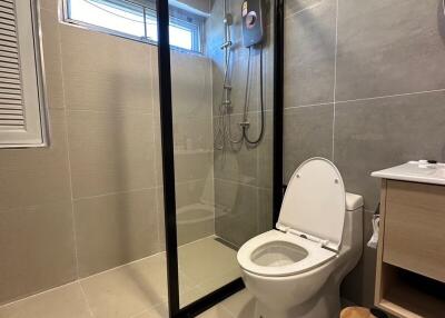 Modern bathroom with glass shower door and grey tiles