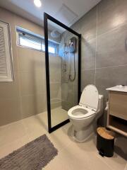 Modern bathroom with glass shower door and grey tiles