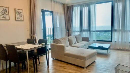 Living room with dining area, large window with a seaside view