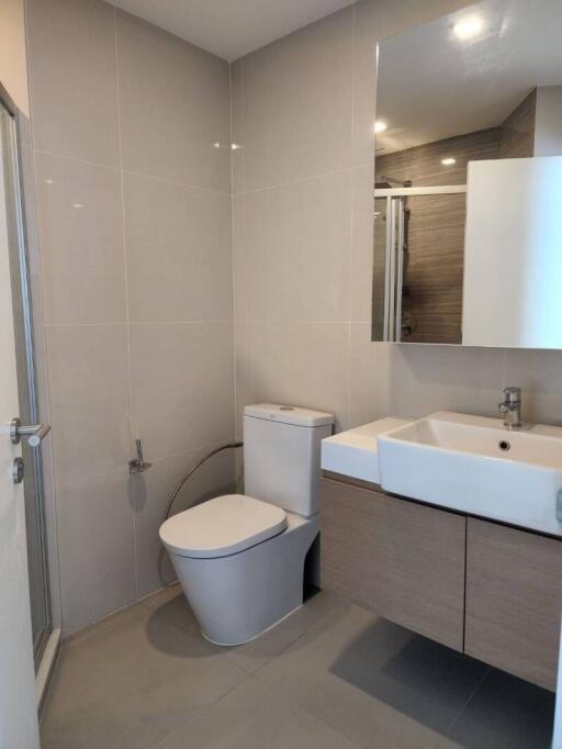 Modern bathroom with toilet, sink, and mirror