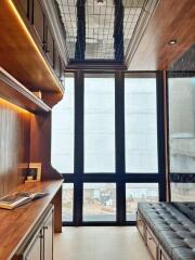 Well-lit home office with wooden furniture and high ceiling