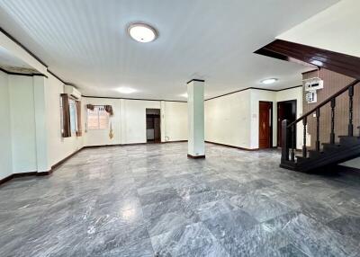 Spacious open-plan living area with tiled flooring and staircase