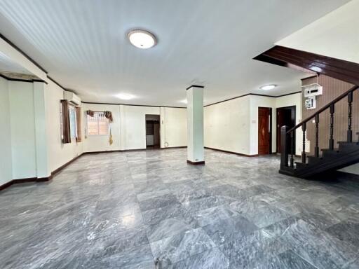 Spacious open-plan living area with tiled flooring and staircase