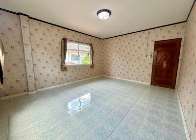 Empty bedroom with floral wallpaper and tiled floor