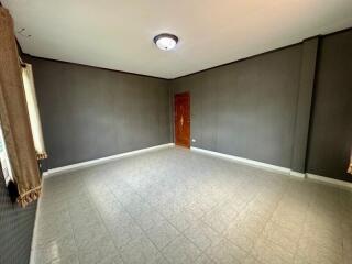 Spacious empty living room with tiled floor and a wooden door