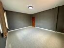 Spacious empty living room with tiled floor and a wooden door