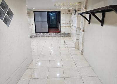 Spacious tiled hallway with wall-mounted shelf and glass door entrance