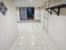 Spacious tiled hallway with wall-mounted shelf and glass door entrance