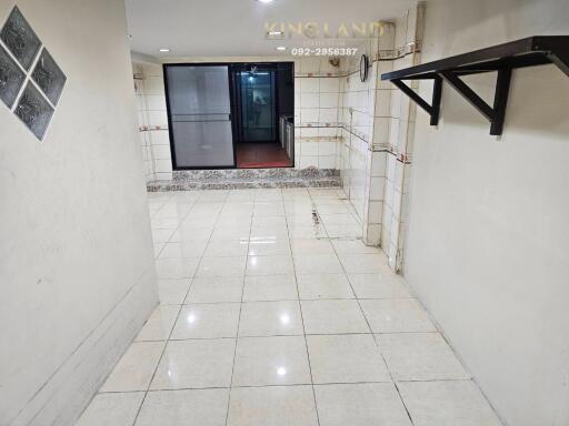 Spacious tiled hallway with wall-mounted shelf and glass door entrance