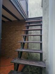 Exposed wooden staircase with brick wall