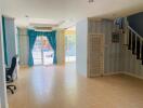 Spacious living room with tiled floor, blue curtains, and staircase