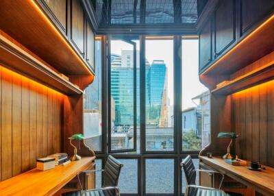 Well-lit office space with wooden shelves and desks, featuring a city view