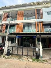 Three-story residential building with balconies and a gated entrance