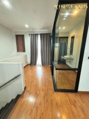 Modern hallway with wooden flooring, glass walls and a staircase