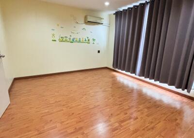 Spacious empty bedroom with wooden floor and dark curtains