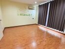 Spacious empty bedroom with wooden floor and dark curtains